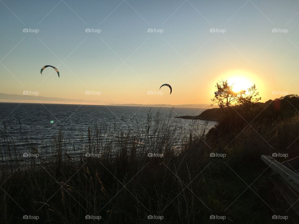 View of para gliders over sea at sunset