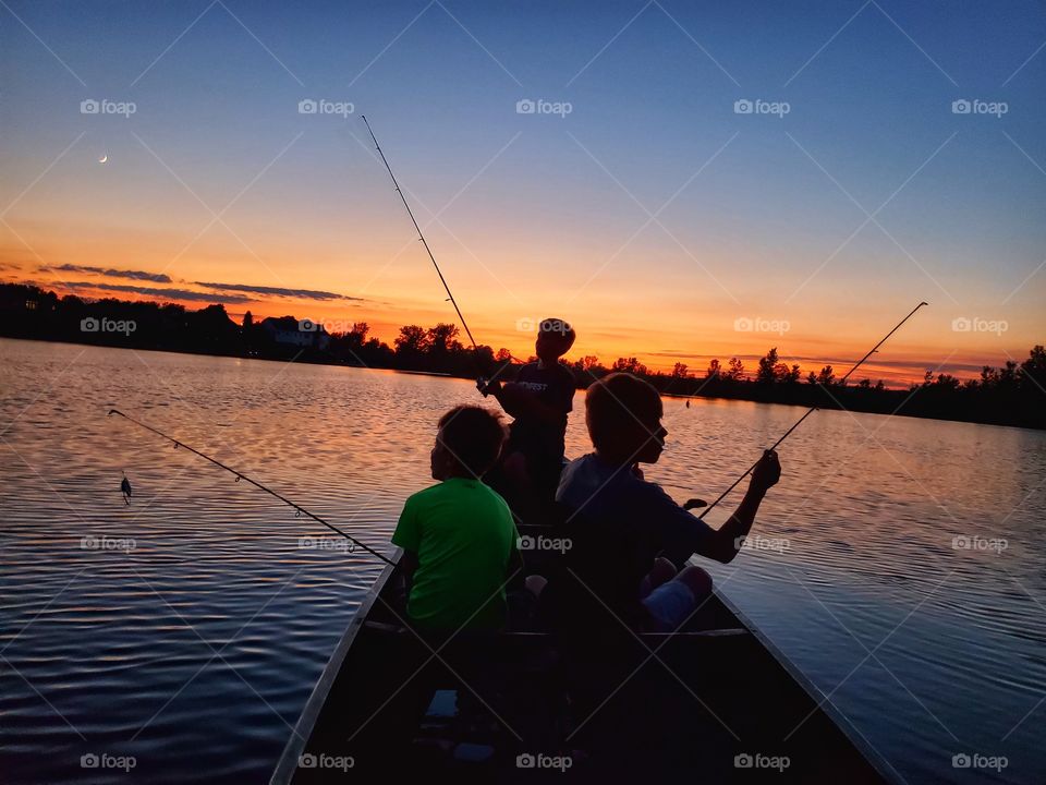 boys fishing from Canoe at sunset