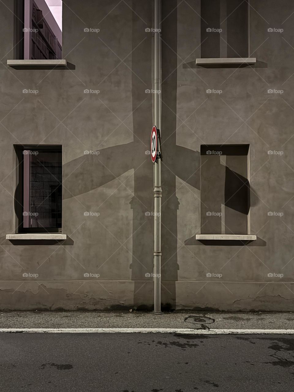Empty Italian street in the evening with interesting shadow from road sign, grey, black and white with red restricting sign 