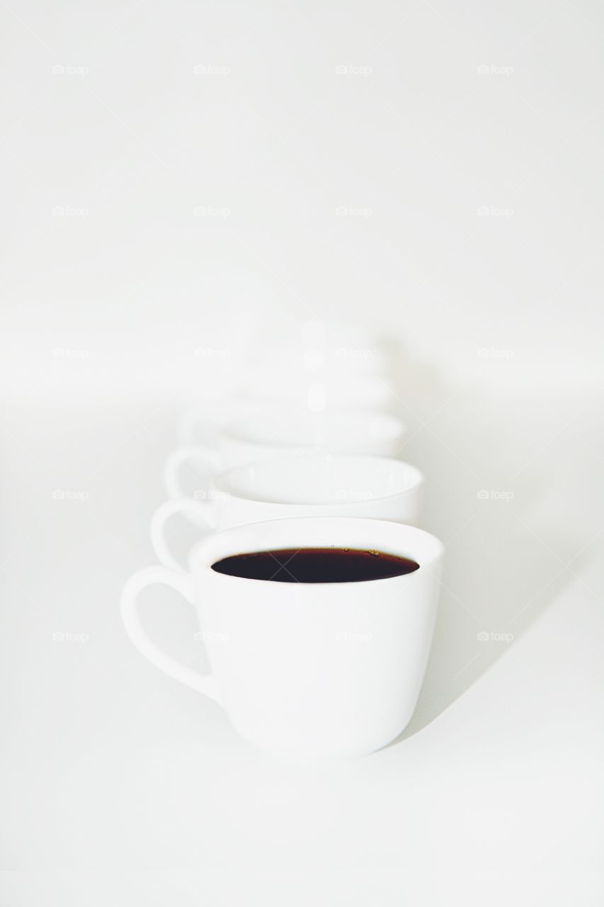 Row of white ceramic coffee cups on white background. Minimalism.