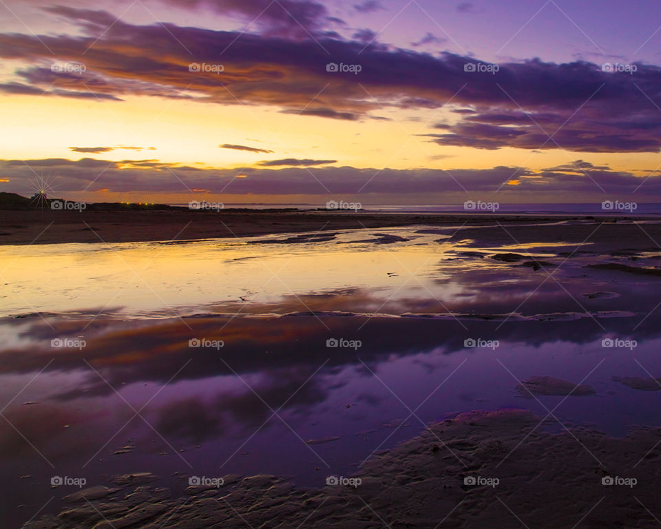 Sunset over Bramburgh Beach. The setting sun and beautiful reflections on the water 