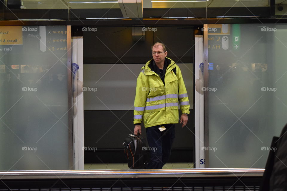 Man wearing high visibility jacket and holding bag