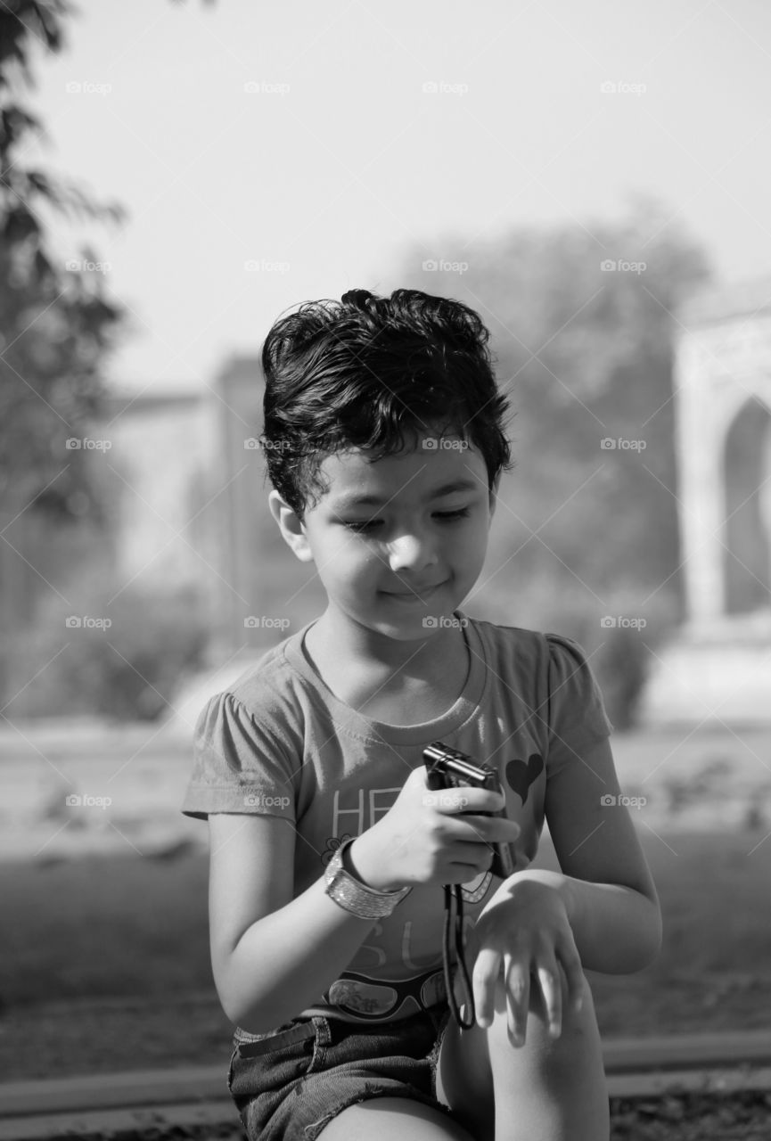 Child enjoying holiday. Child portrait. I took this photo of my daughter while on a trip to city tour. Today's kids are very intelligent and advanced and are tech savy. She is holding a point and shoot camera and she also took along with me some beautiful pics. I was very happy to see this.
