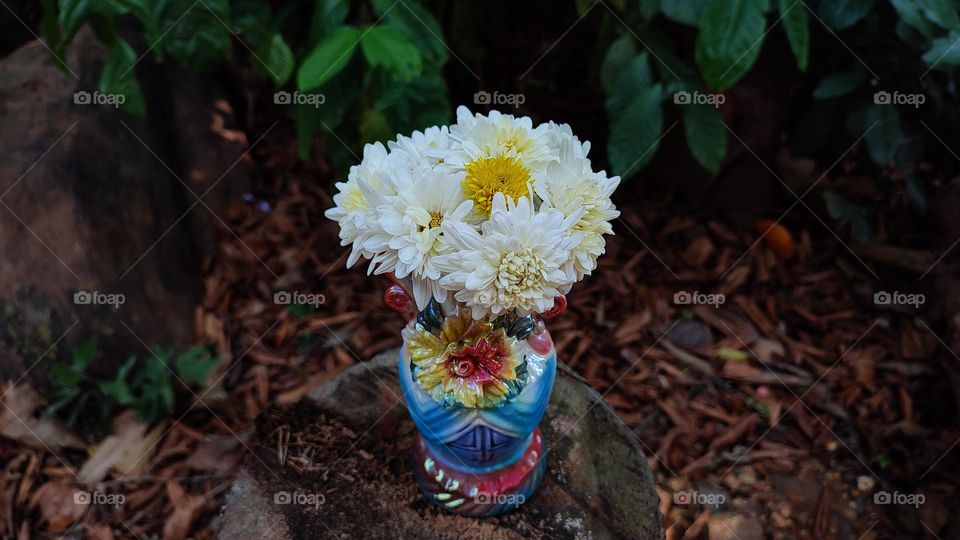 Beautiful white flowers in a colourful flowerpot with a flower sculpture, Flowers in a vase, colourful vase, white flowers in a vase