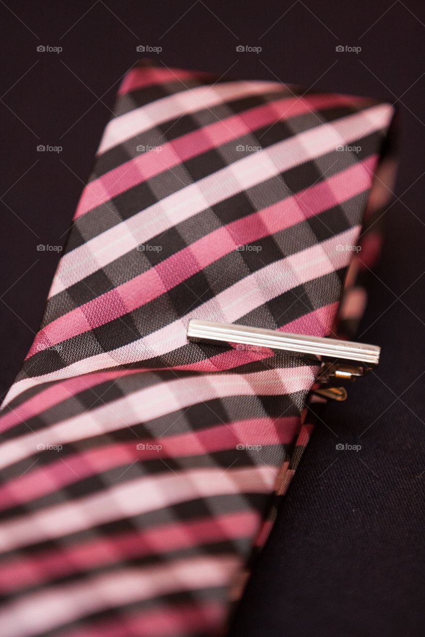 Close up of striped tie in pink and black with clip