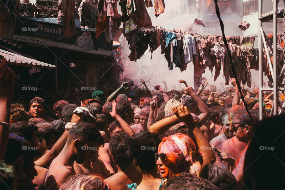 People throw clothes and colourful powder in a crowded square during Holi festival in Pushkar, India.