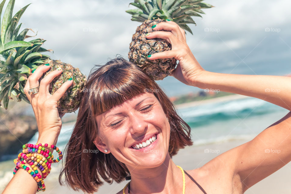 Funny girl having fun on the beach with pineapples.