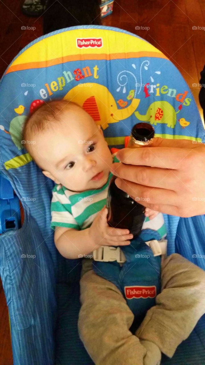 Baby looks at a beer bottle with a funny look!