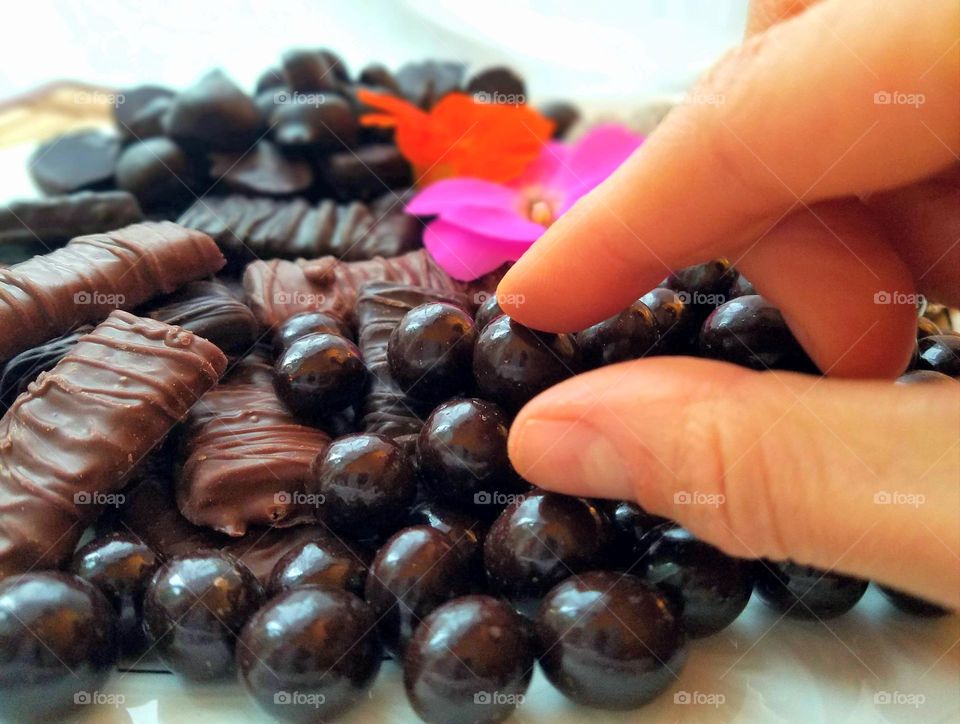 hand selecting chocolate from candy plate with flowers