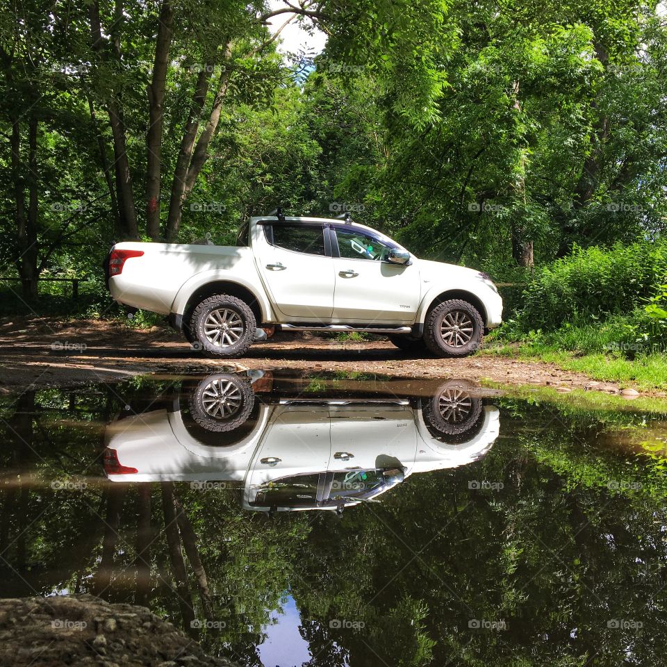 White car/van parked next to a puddle of rainwater 