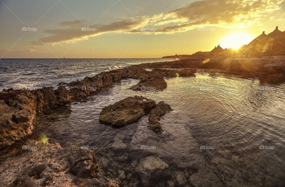 A corner of paradise: A natural pool in the middle of the rocks that make up the coast in the Mexican Caribbean at Puerto AVenturas at sunset.