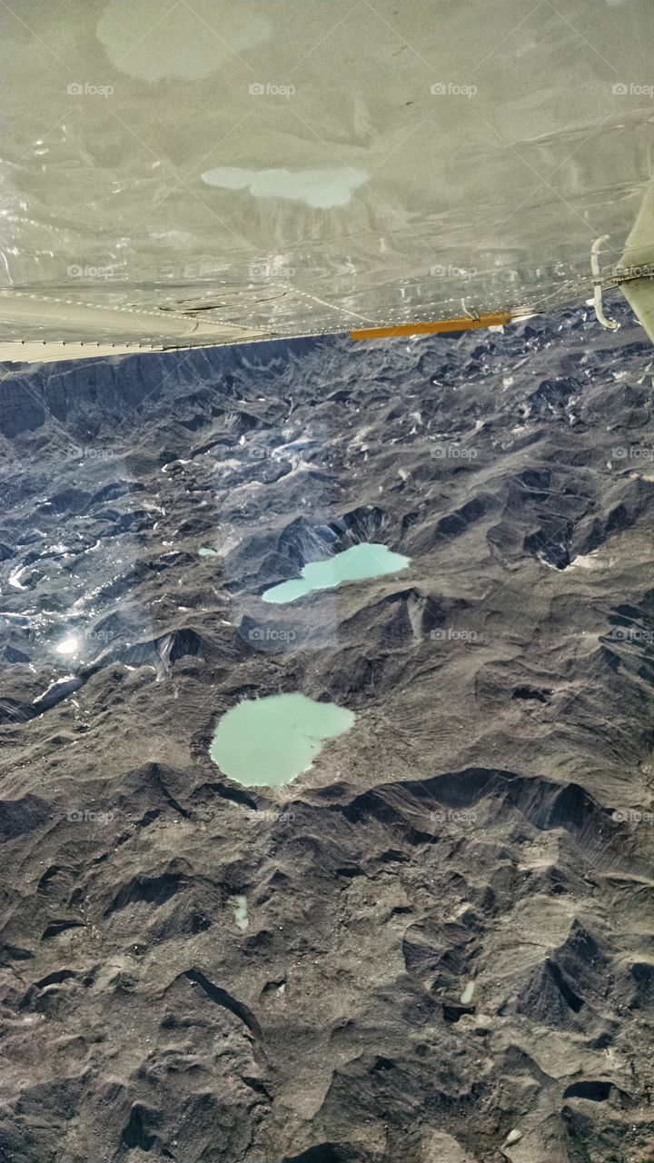 Glacier pools reflecting on the plane wing.