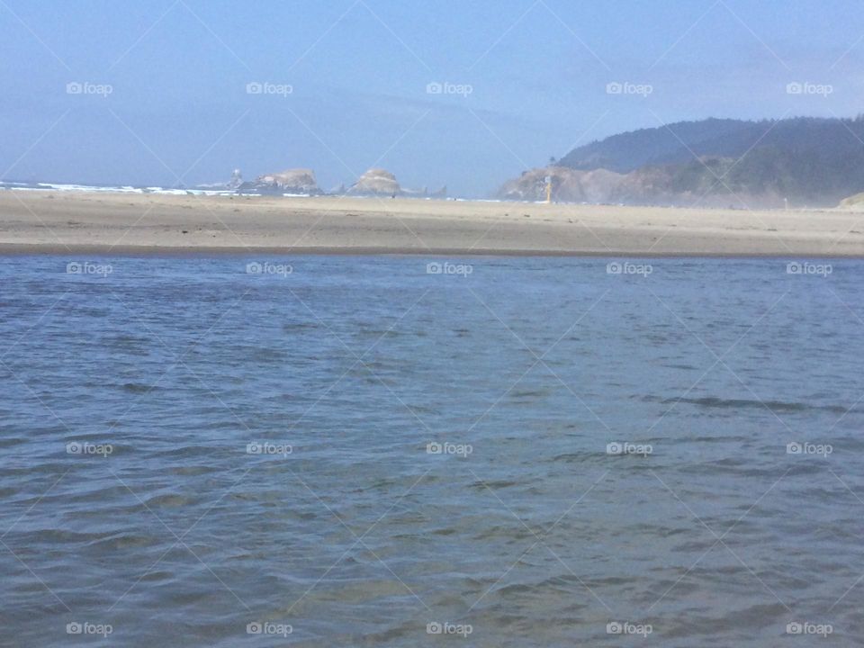 The white sand along Cannon Beach, Oregon with the mountains and rock formations in the Distance 