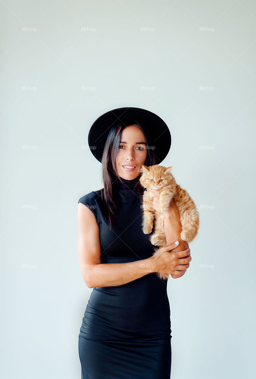 girl in a black dress with a red kitten in her hands