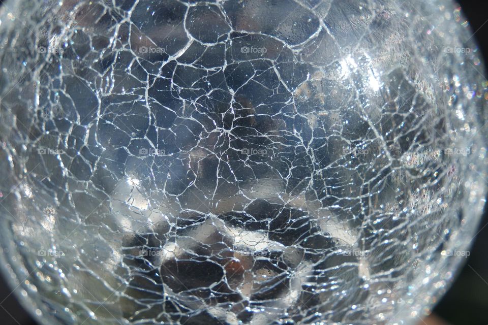 Shattered style of glass on a ball, clear and reflective, with blues, greens, black, basically the whole rainbow if you look close enough!