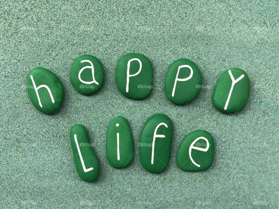 Happy life with green colored stones over green sand