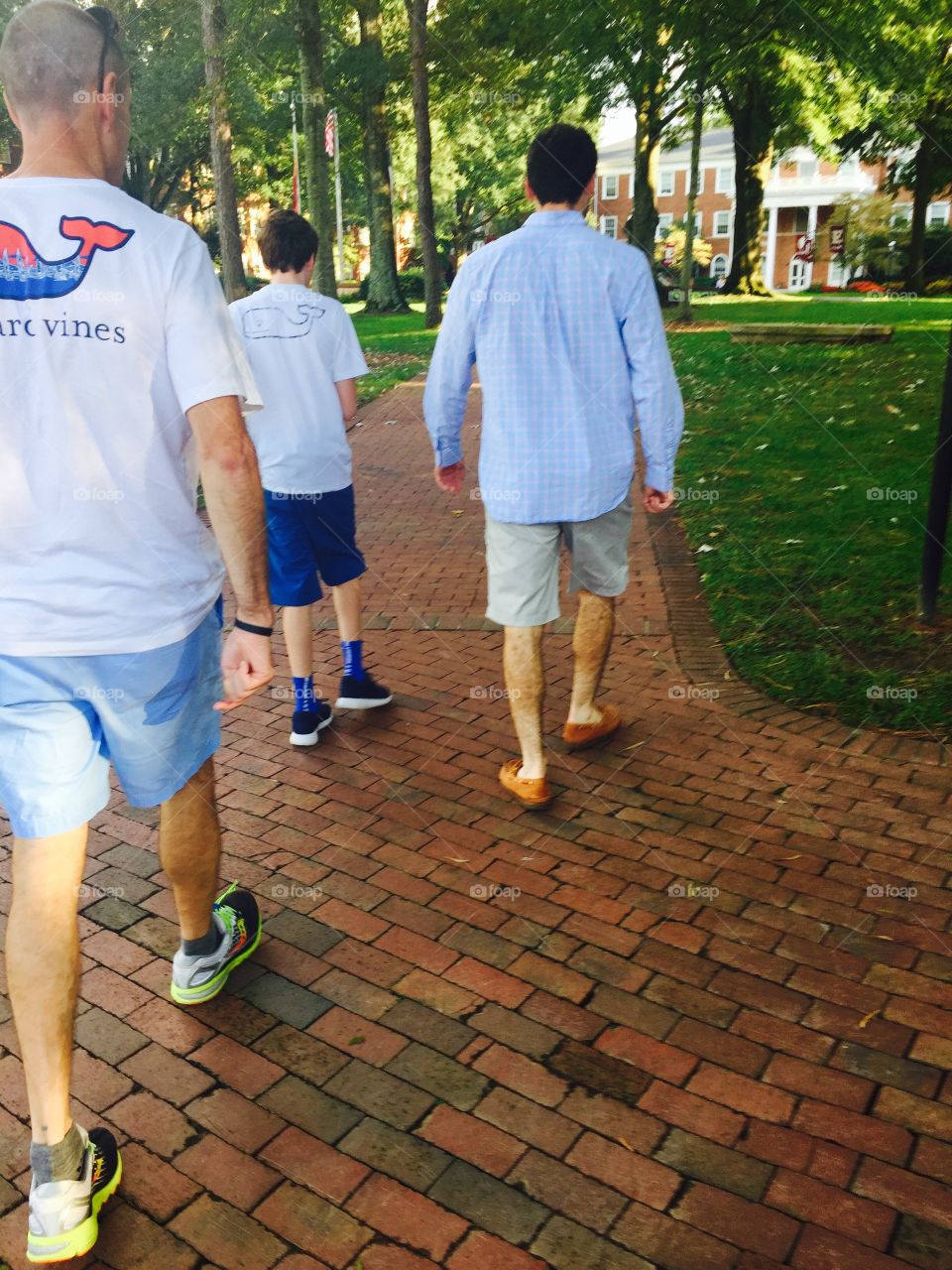 Father and sons from behind on brick pathway