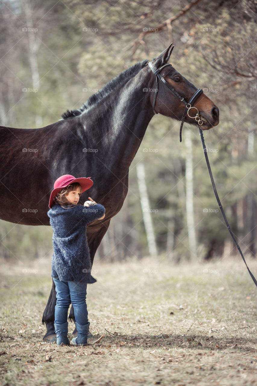 Little girl with horse, outdoor portrait 