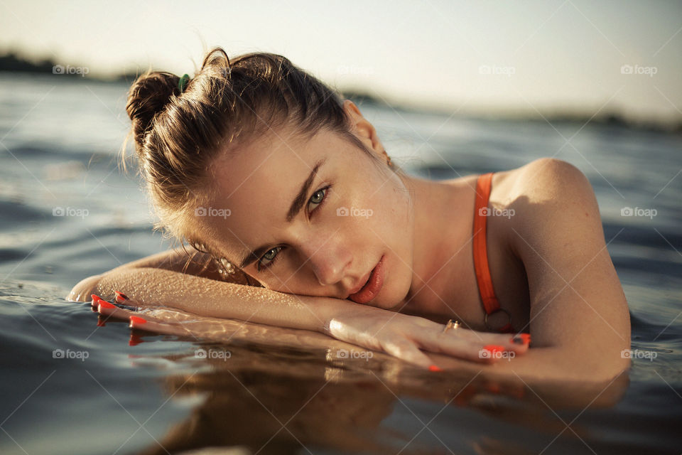 Fashion photo of a girl in the water. Portrait photo of a beautiful girl at the sea. summer fashion portrait of pretty brunette girl posing in blue water.
That look is very effective.