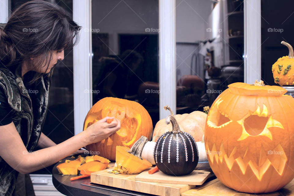 Woman carving pumpkins and making various pumpkin decorations at home carved and home craft painted and decorated pumpkins 