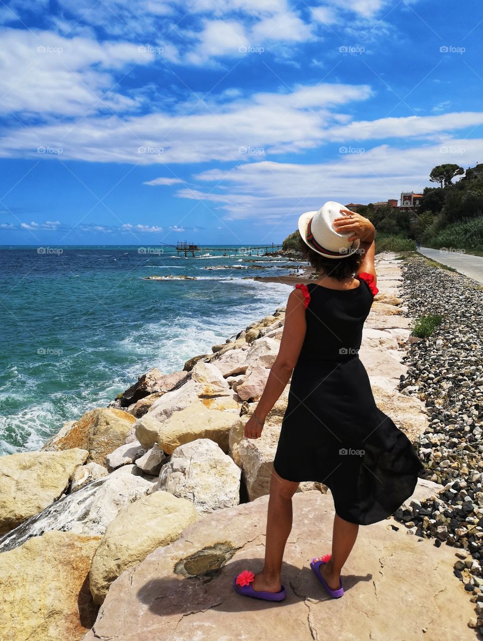 woman with black dress looks at the sea