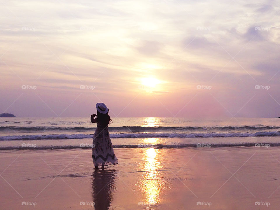 Young woman enjoying the pink sunset over the sea