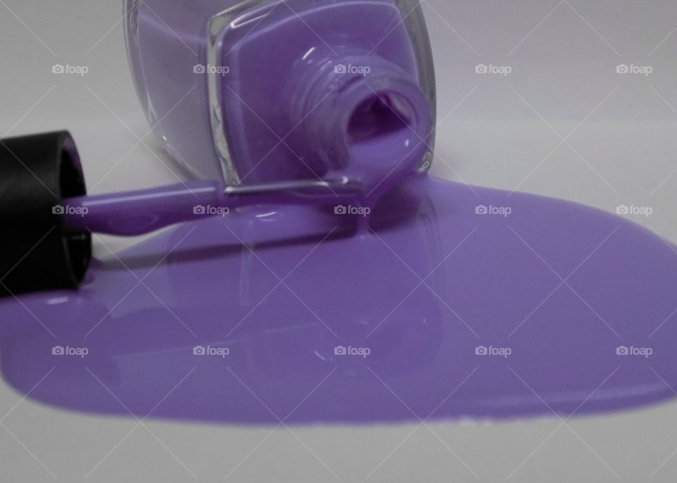 Purple nail polish pouring out of bottle