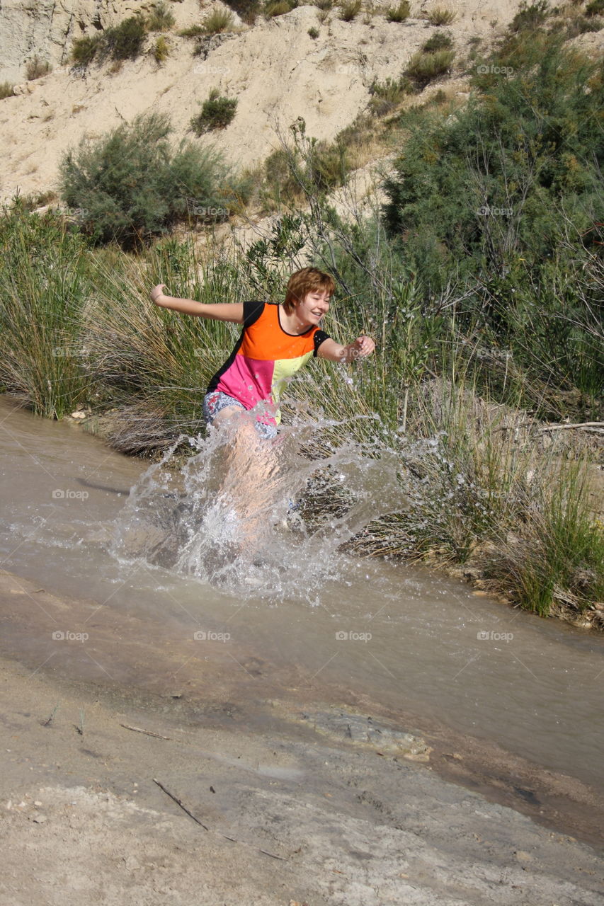 Running down the river making sure the water splashes. The main object is the water. Then I run out and trees and plants appear in the background.