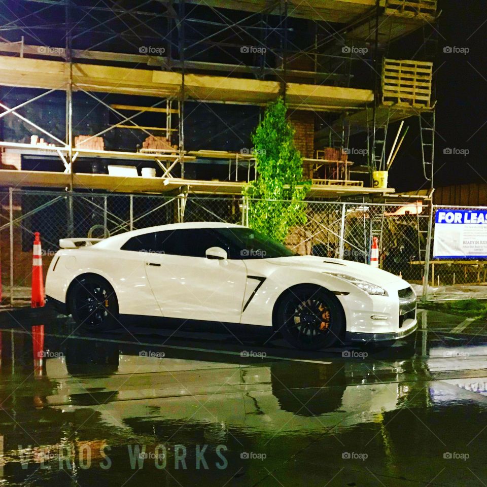 Night life of the car scene. A Nissan R35 parked under the street light after a fresh rain on an urban city street. 