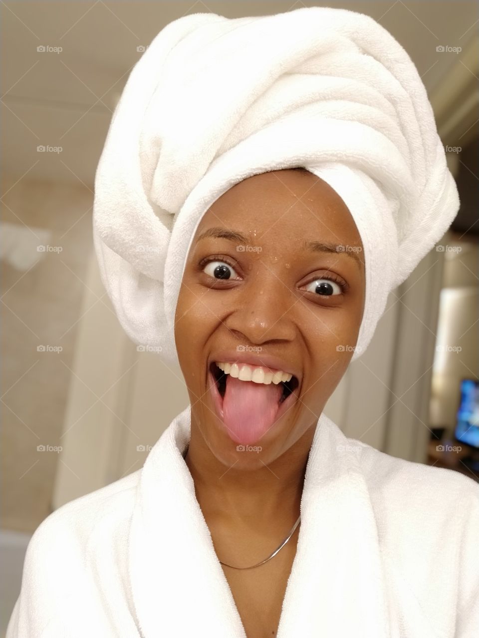 Happy lady wearing a white bath robe and towel with her tongue stuck out