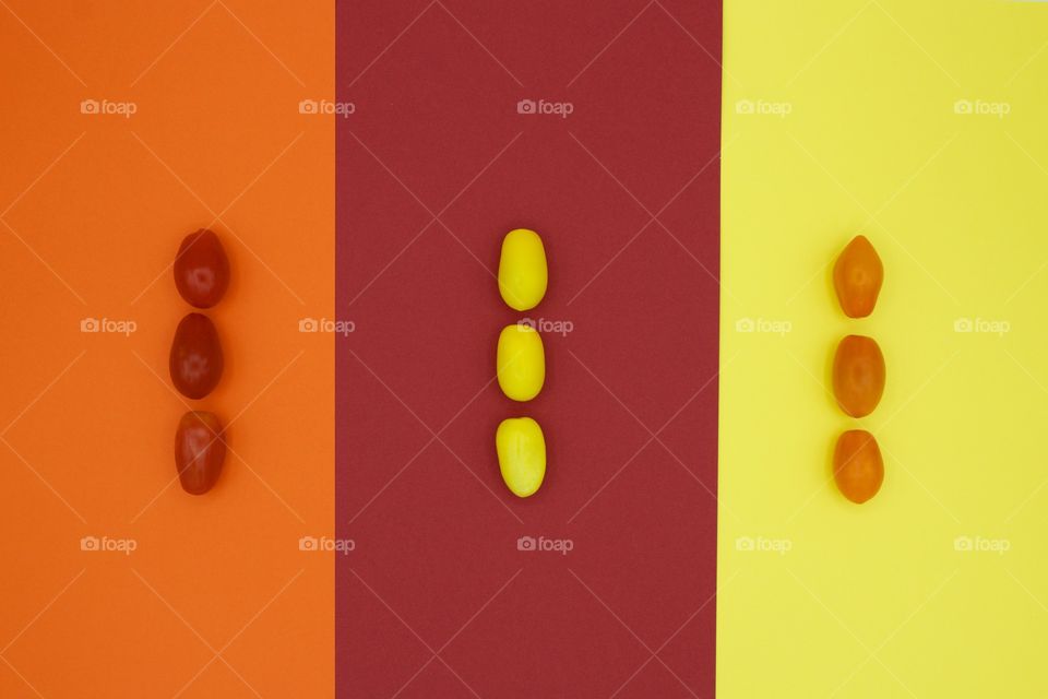 Color Love - flat lay of heirloom medley cherry tomatoes in red, yellow and orange, arranged vertically in threes on orange, red and yellow paper