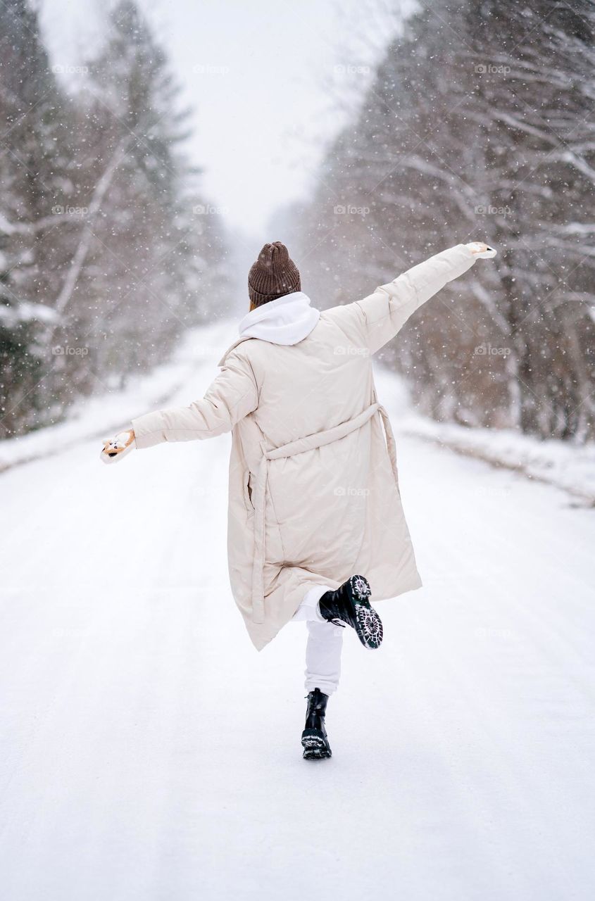 Woman in white warm jacket walks in the forest. Enjoying winter. Wonderful snowfall