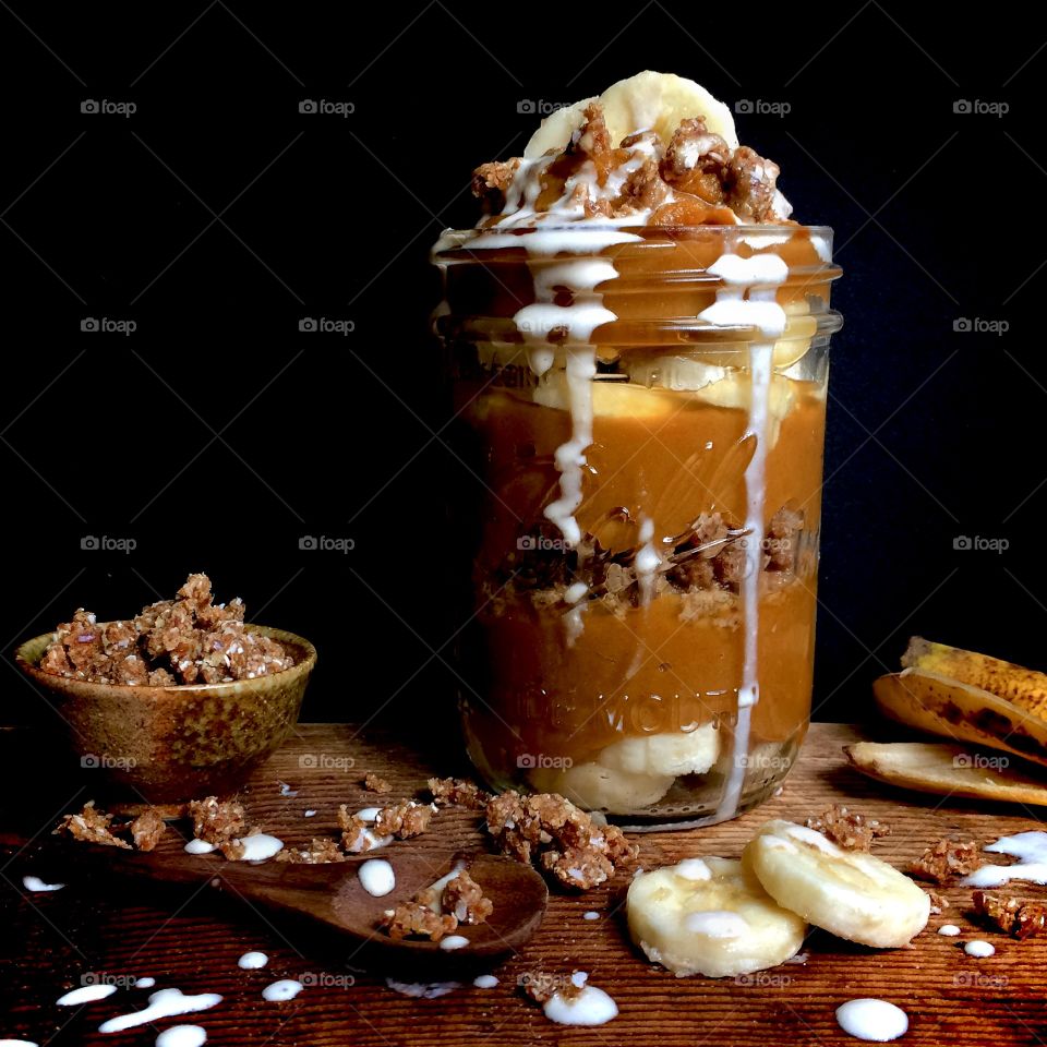 Pumpkin Pie custard and sliced bananas in a glass with cream and crumble topping.