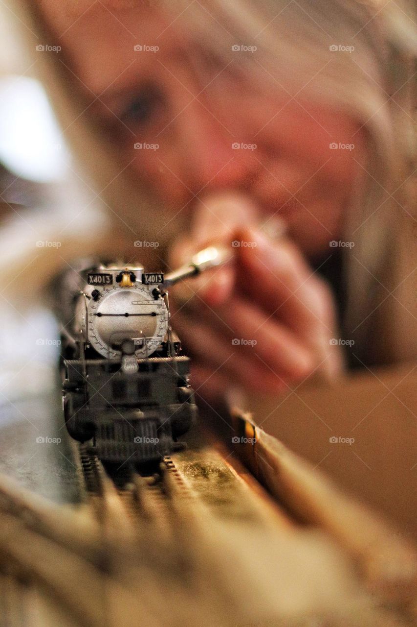 A woman repairs a model train using a special tool