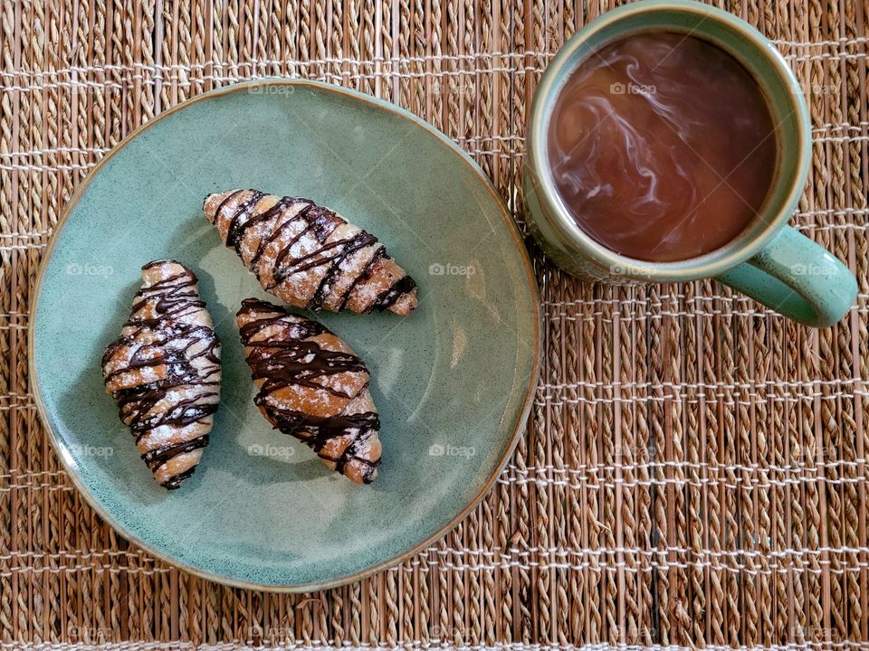 Morning time, simple breakfast of chocolate croissants and coffee on bamboo placemat