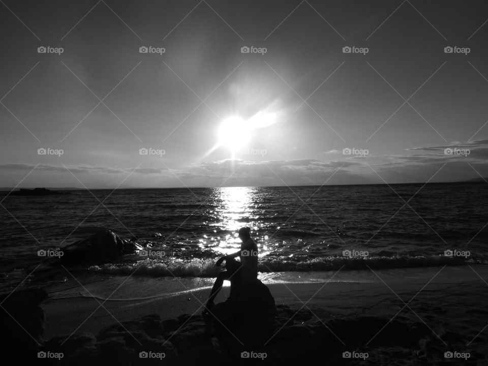 lonely girl seating od rock and waiting for her love,on sunset on the beach,monochrome