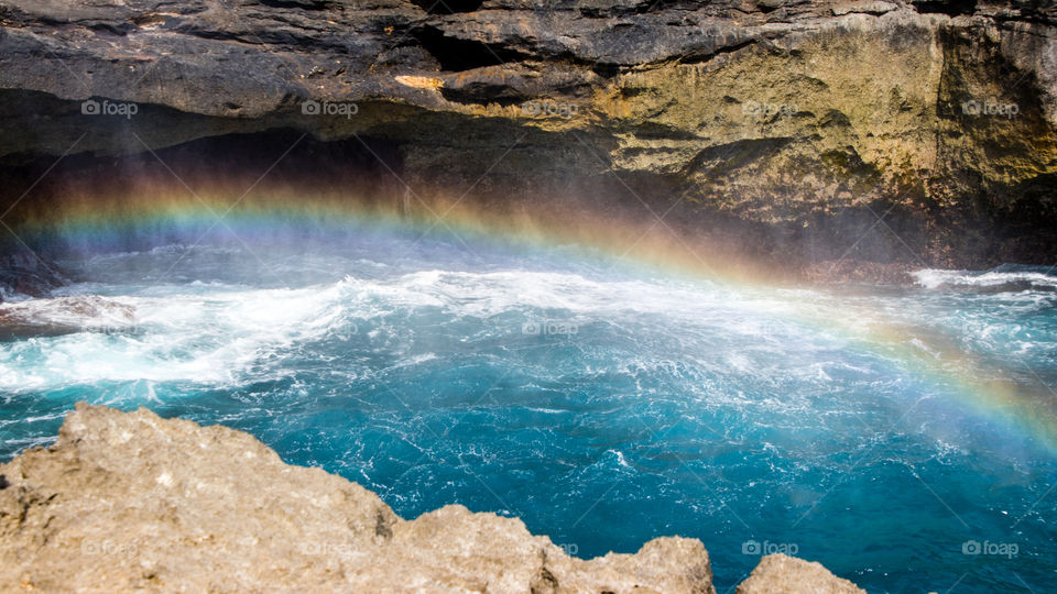 Early morning rainbow over the cliffs of the Devil's Tear of Nusa Lembongan Indonesia