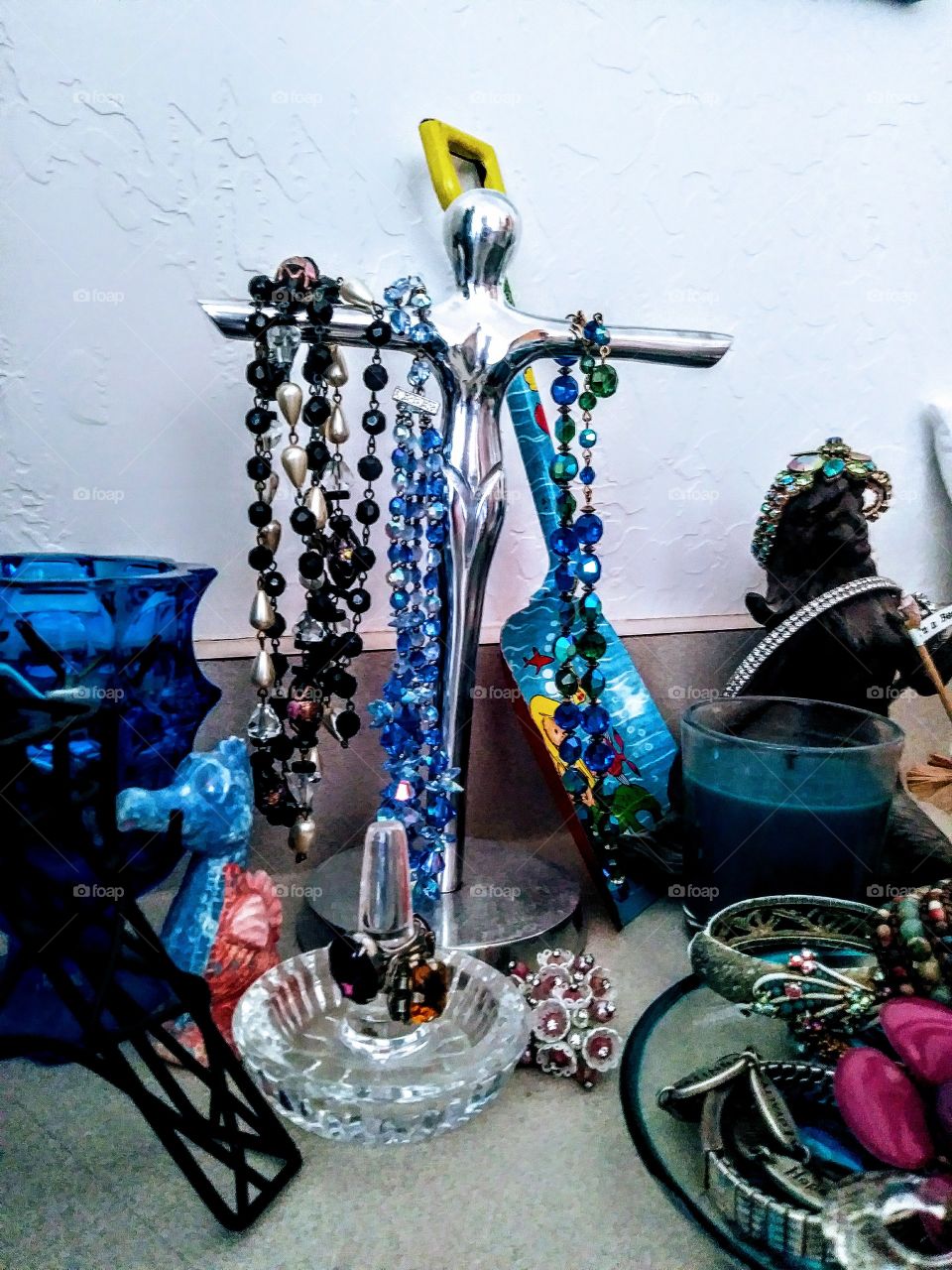 jewelry hanging on woman shaped silver stand on counter top cluttered