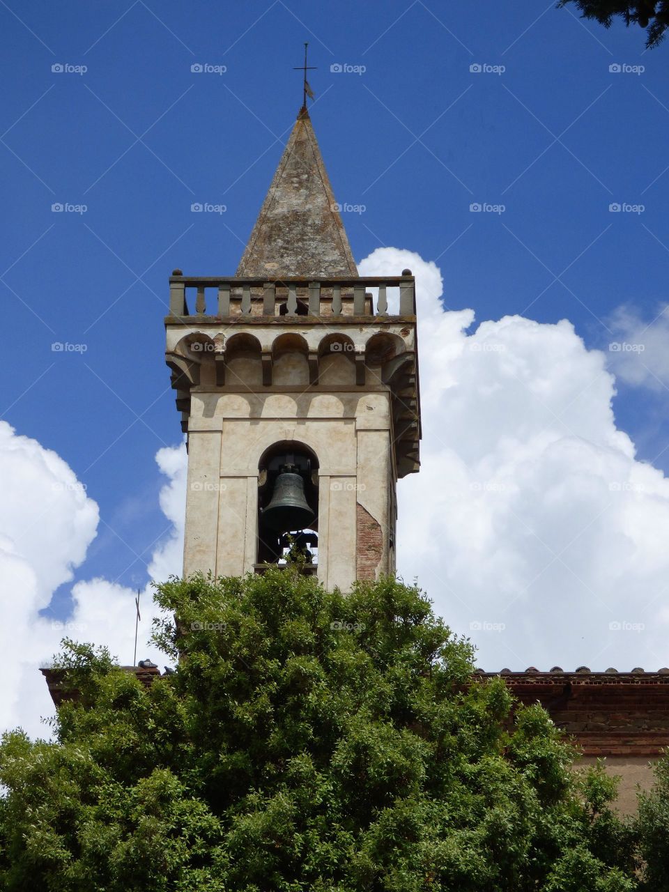 Medieval Bell tower in Volterra Italy with a blue sky and white clouds background.