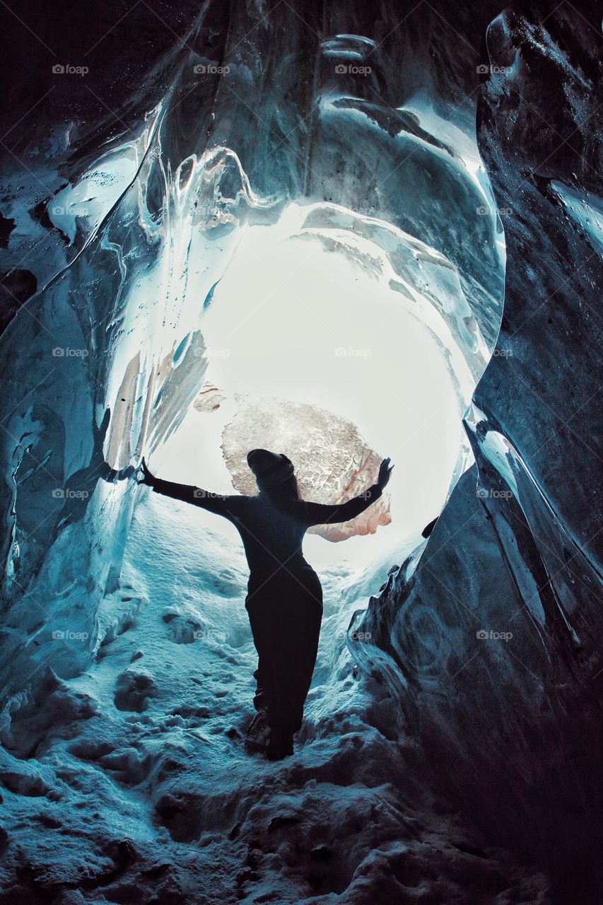 The girl stands in the opening of the ice cave