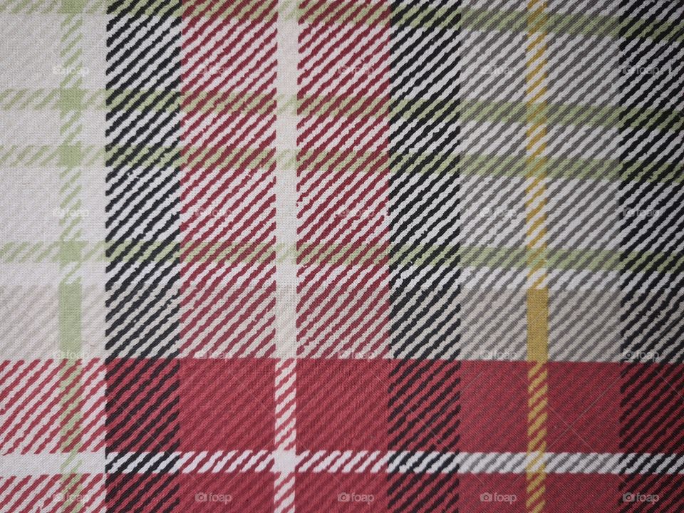 Scottish-like squares and check pattern of a fabric in green, yellow, red, white and dark blue colors.