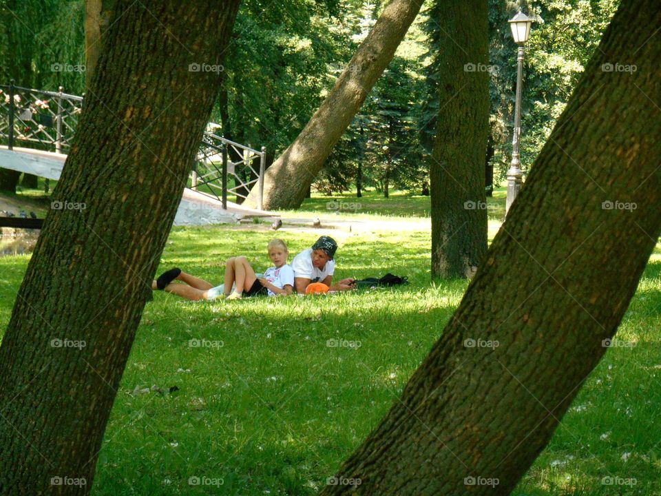 father and son resting on a green grass in the summer park