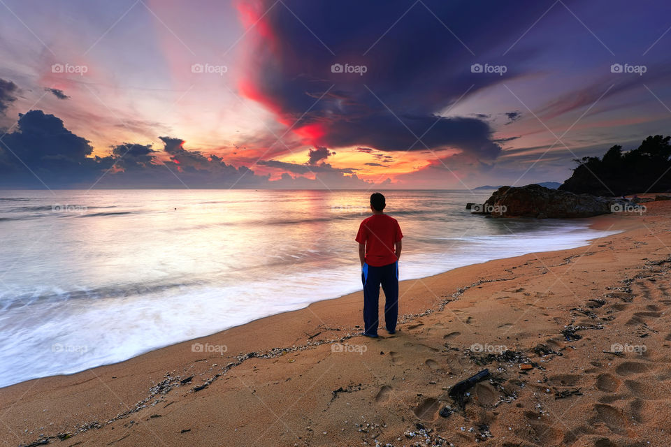 Man standing at the beach watching beautiful sunrise
