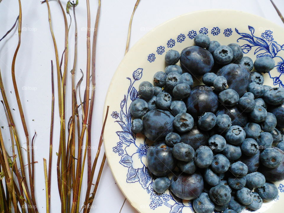 Berries of blueberries and plums on a white plate