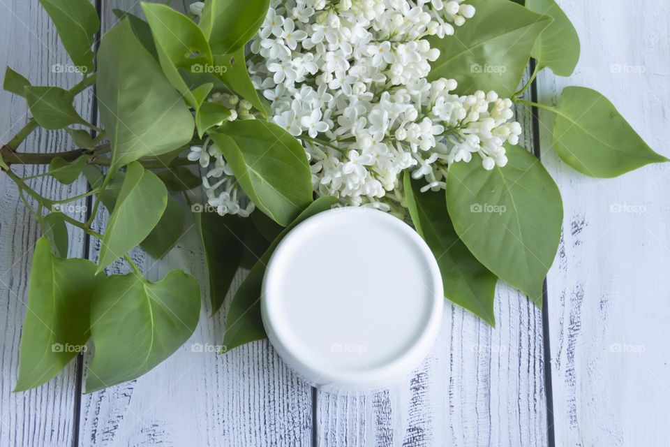 Spring, white fragrant lilac with green leaves.  and jars with cosmetic cream and product.