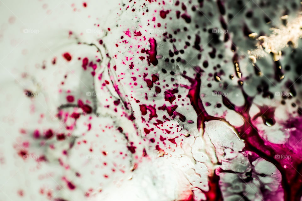 Black and pink refill ink spilled onto the white sink and the ink mixed into abstract blobs and patterns.
