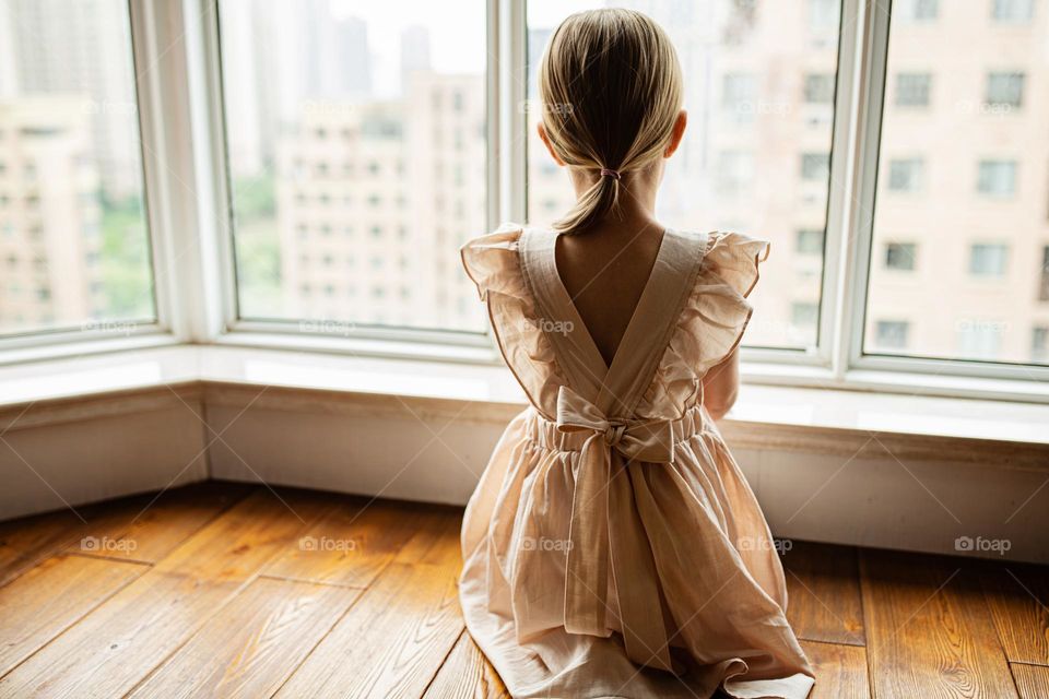 Little girl sitting near window 