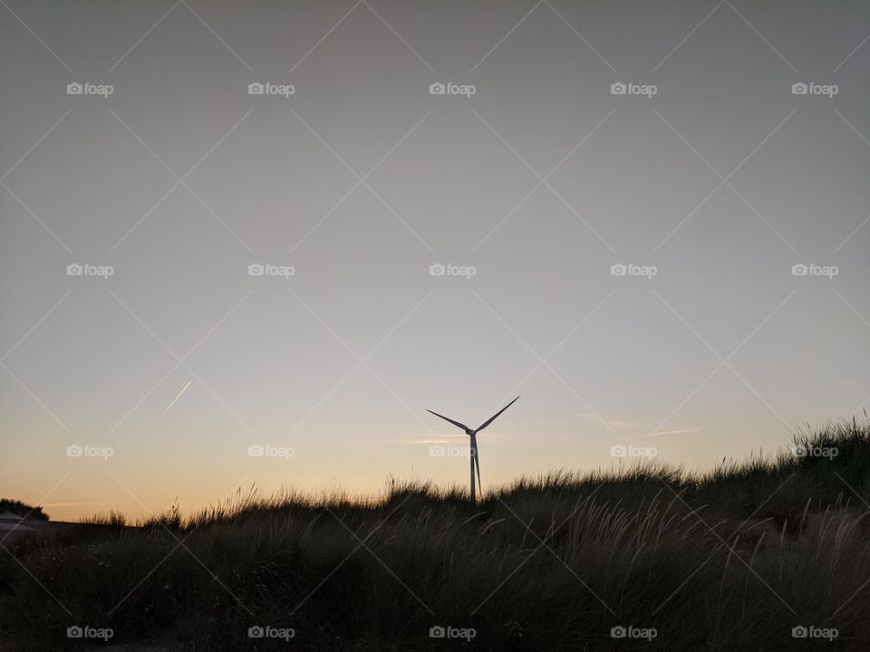 Wind turbine in dunes at sunset