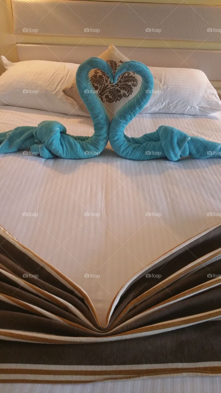 2 towel swans on a bed of an hotel bedroom