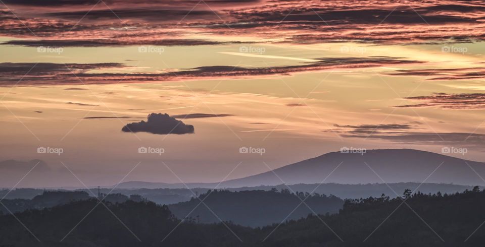 A dusky after sunset sky silhouettes hills and mountains 